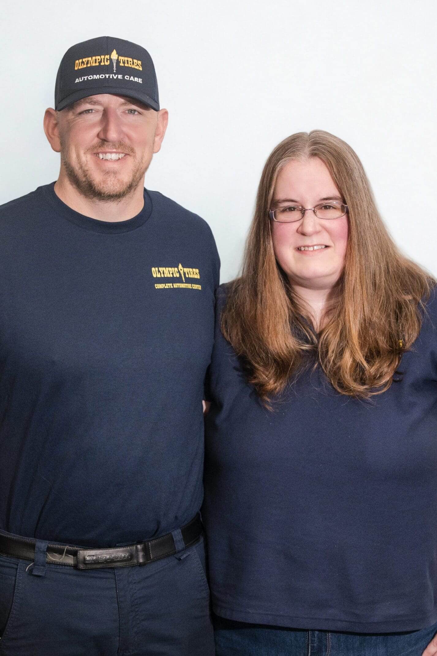 Two people smiling, wearing matching navy blue shirts.