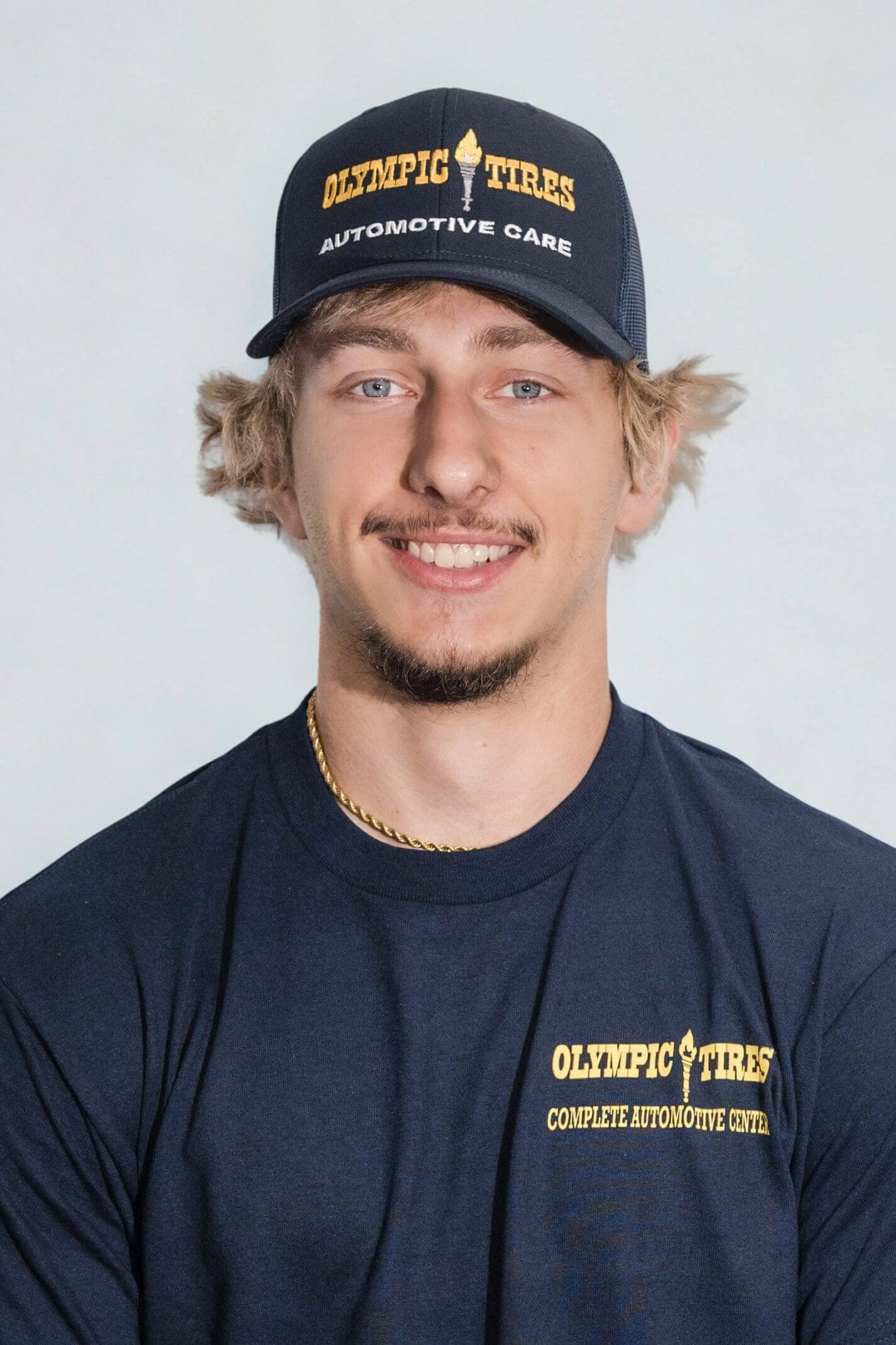 Young man wearing a navy blue cap and matching t-shirt with a logo.