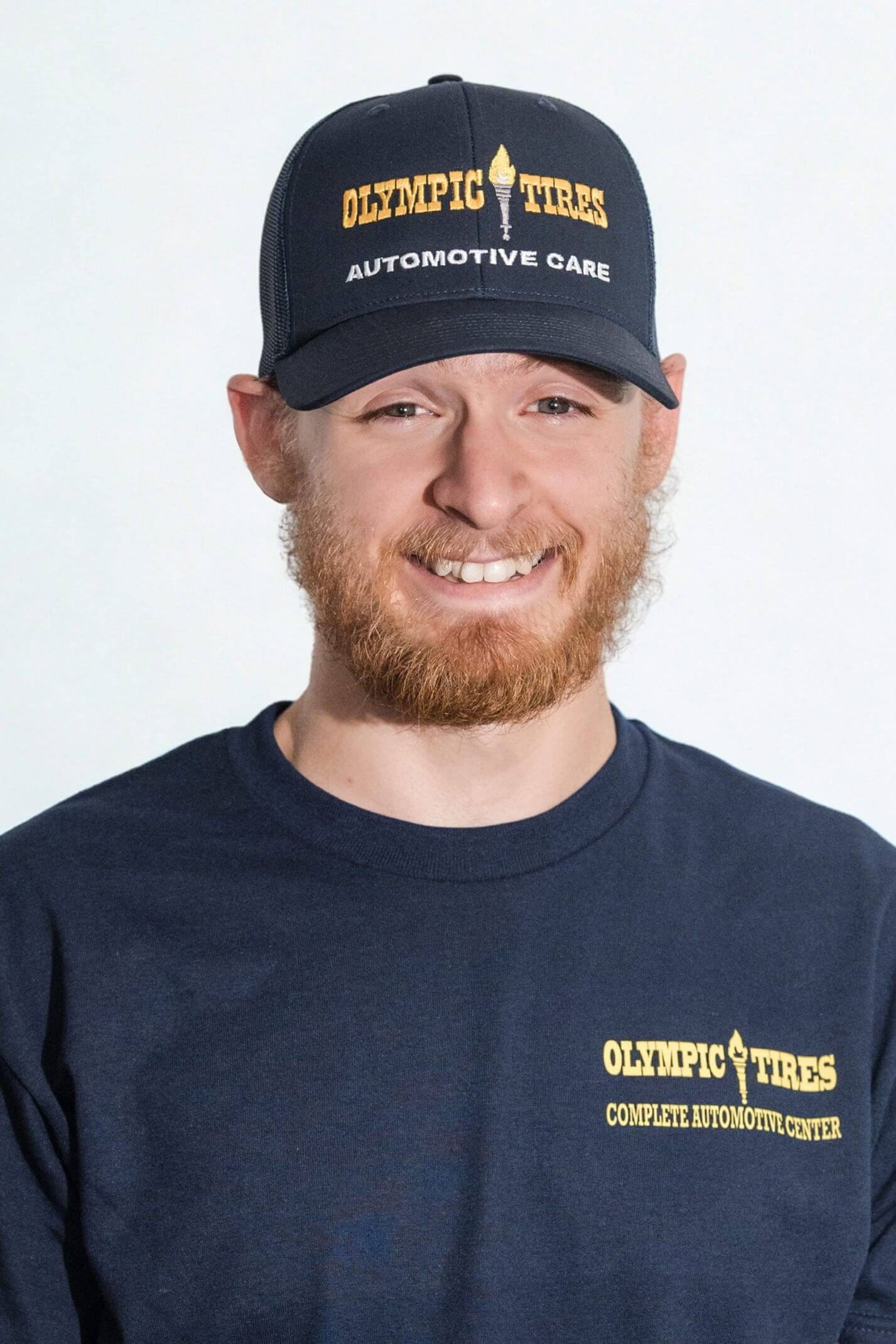 Smiling man with a beard wearing a black cap and dark t-shirt.