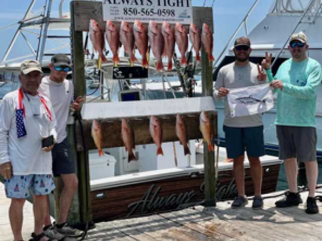 Two men proudly display their catch of fish on a dock.