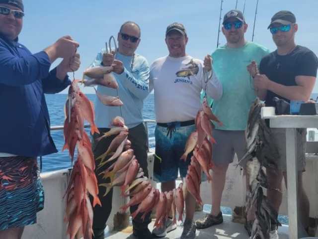 Group of men proudly displaying a large catch of fish after a successful fishing trip.
