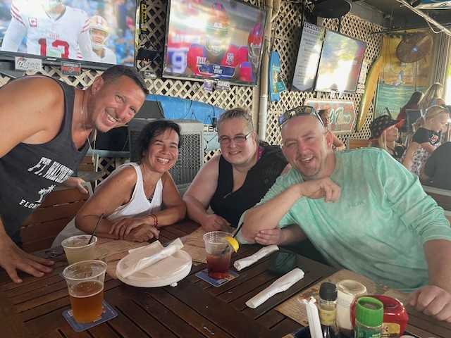 Four friends enjoying drinks and food at a lively bar.